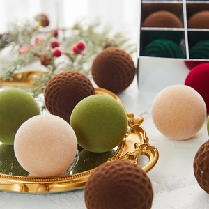 Close-up of 6cm flocked Christmas balls with geometric textures on a vintage tray