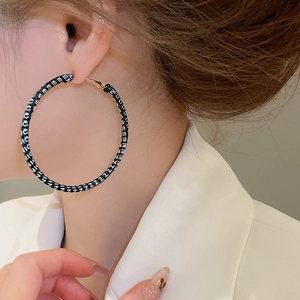 Gros plan de grandes boucles d'oreilles créoles avec tissu monogramme noir et blanc