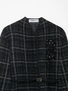 Detail of dark grey plaid knit coat with black sequin floral embroidery and thin belt