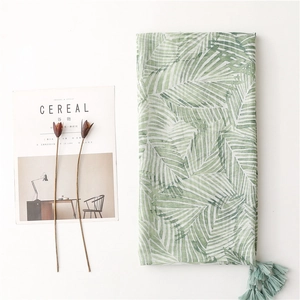 Flat lay detail of lightweight bohemian scarf with green leaf pattern and tassels