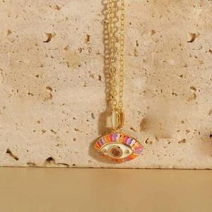 Detailed view of evil eye necklace with pink zircon and gold finish on stone background
