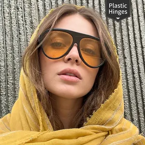 Fashionable oversized aviator sunglasses with orange lenses and black plastic frame on model
