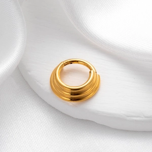 Macro detail of golden multi-layered seamless nose ring on white silk background