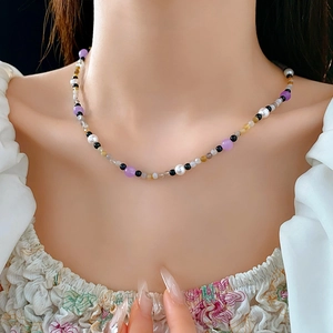 Detail of colorful pearl beaded necklace with purple, black and white stones on neck