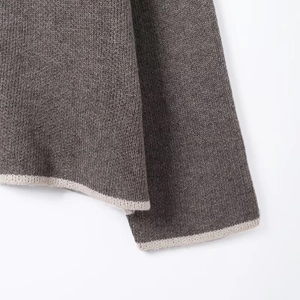 Close-up of charcoal grey knit top showing detailed cuff and hem with cream trim