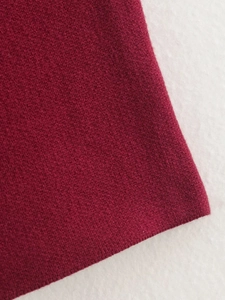 Détail macro montrant la texture en maille bordeaux de qualité et le tissage côtelé fin