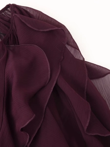 Dettaglio di volant a strati su una camicia di chiffon viola scuro con cuciture fini