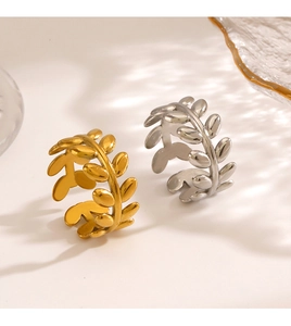 Detail view of gold and silver leaf pattern adjustable stainless steel rings in soft light