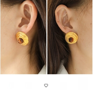Macro shot of gold spiral earrings featuring centered brown tiger eye stone on ears