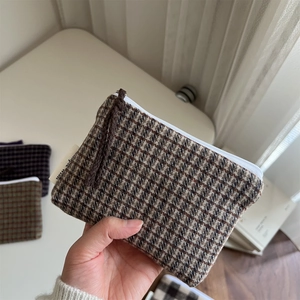 Close-up of a retro plaid tweed coin purse with a durable zipper and brown woven puller