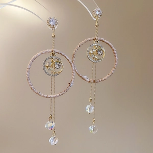 Detail of long tassel earrings with woven rings, crystal star pendants and gold chains