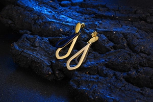 Detailed view of teardrop titanium earrings with deep blue inlays on dark charcoal