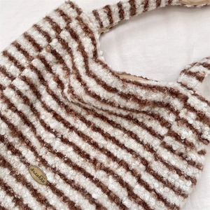 Close-up of fuzzy brown and white striped tote bag with oval metal logo detail
