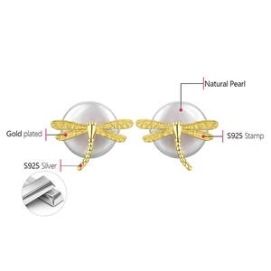 Macro detail of S925 sterling silver gold-plated dragonfly earrings with natural pearls