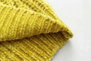 Macro view of bright yellow chenille knit fabric showing thick ribbed texture and soft feel