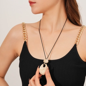 Macro view of beige teardrop stone pendant with marble texture on a black wax cord