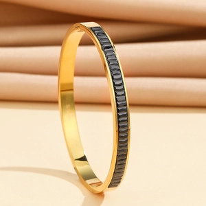 Close-up of gold stainless steel bangle with black rectangular inlay and S.Steel hallmark