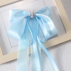 Macro shot of light blue satin bow hair clip with pearls and long chiffon ribbons