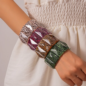 Close-up of four colorful acrylic leopard print wide bangles on a model wrist