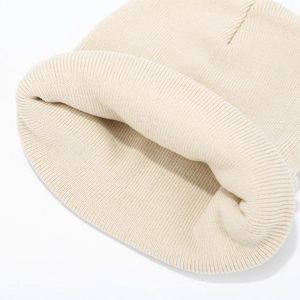 Detailed close-up of ribbed knit beige beanie showing thick folded cuff and texture
