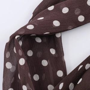 Detail of sheer brown polka dot fabric showing lightweight texture and drape