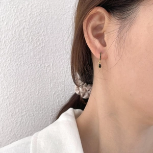 Detail of gold hoop earrings with black zircon stones and water drop pendant on ear