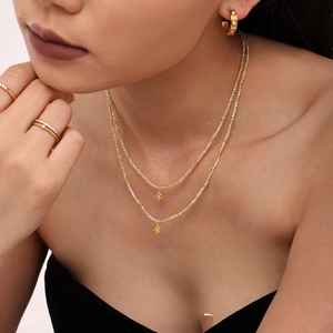 Detail of double-layer beaded necklace with gold star pendants and 18k gold plating