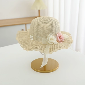 Close-up of hand-woven straw hat with wavy brim and delicate floral ribbon accents