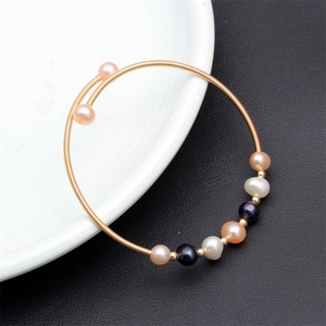 Macro detail of mixed color natural freshwater pearls woven on a gold wire bracelet