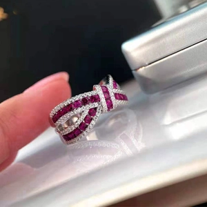 Macro detail of silver bow ring featuring pavé-set red gemstones and white crystals