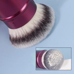 Close-up of dense retractable powder brush with purple metal handle and gradient bristles