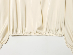 Vue macro du tissu en satin soyeux et de l'ourlet élastique d'un chemisier en V