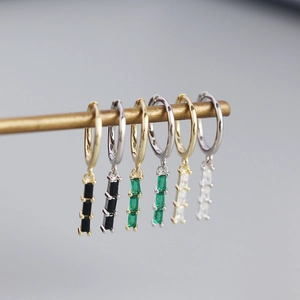 Detailed view of gold and silver rectangle zircon earrings hanging on a metal rod