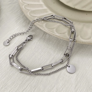 Detail of silver double-layered titanium steel bracelet with paperclip chain and round charm