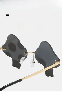 Detail of mushroom-shaped rimless sunglasses with gold metal frame and grey lenses
