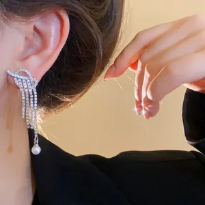 Macro shot of silver pearl tassel earrings with zircons and drop pearls on a model