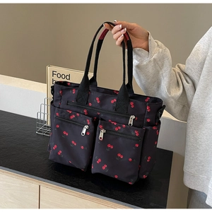 Detail of printed tote bag featuring cherry patterns and multiple functional zipper pockets