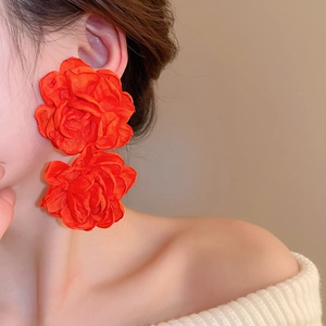 Detail shot of oversized red fabric flower earrings with textured layered petals