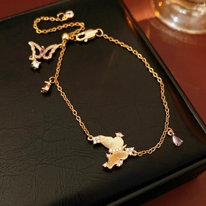 Detailed shot of a gold butterfly bracelet with purple crystals and adjustable slide clasp