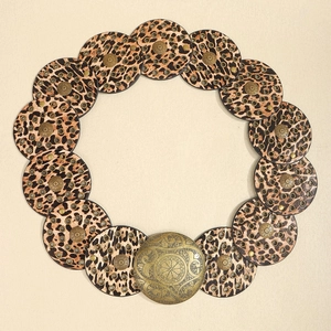 Detail of leopard print leather circle belt with a vintage brass round buckle closure