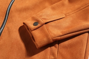 Detail of suede jacket cuff with metal snap button and zipper texture in ginger color