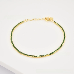 Close-up of golden tennis bracelet with green zircon inlay and adjustable lobster clasp