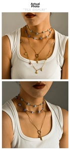 Close-up of layered 18K gold butterfly necklace with shell and star charms on model