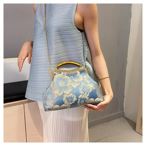 Detail of blue satin bag with gold floral embroidery and metallic frame handle