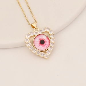 Detailed view of a gold heart pendant with CZ stones and a pink eye motif on a thin chain