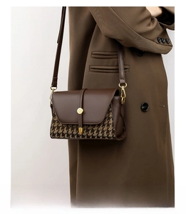 Detail of canvas leather stitching on brown houndstooth bag worn with brown blazer