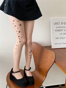 Detail of sheer nude tights with black star prints paired with platform Mary Janes