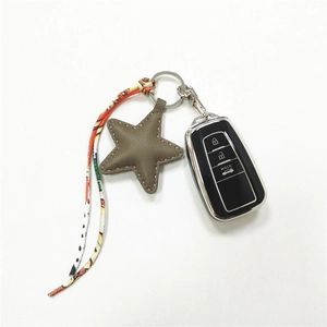 Close-up of khaki leather star keychain with colorful ribbon on black smart car key