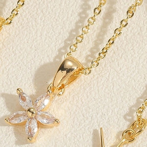 Macro detail of a gold flower pendant necklace featuring clear marquise-cut zircon petals
