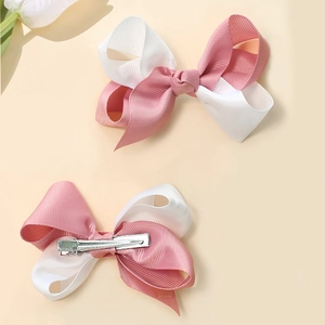 Detail of pink and white ribbon bow hair clips showing front design and metal alligator clip